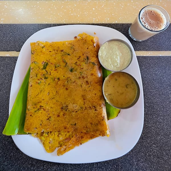 BB's Indian Kitchen's dosa with two chutneys and a glass of chai on a patterned table.